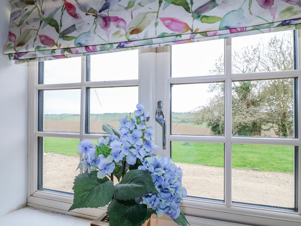 A window with floral curtain and flower pot at America Lodge in Oakham
