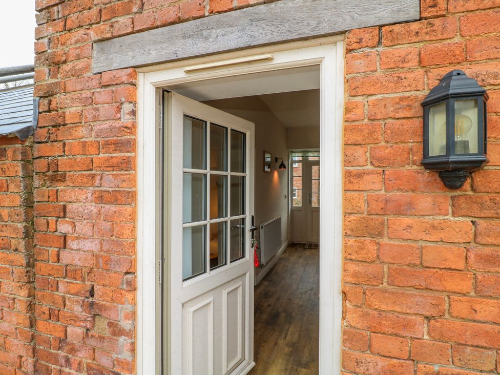 An entrance hallway with a door and brick wall at America Lodge in Oakham