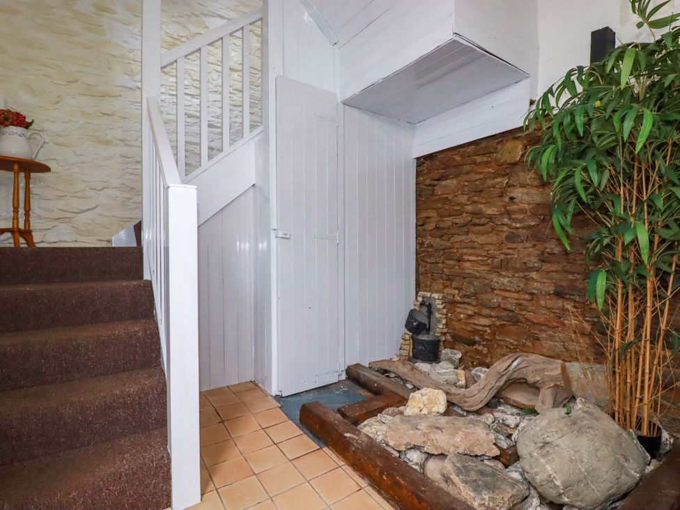 A hallway with stairs leading up and a rock feature at The Penthouse in Looe