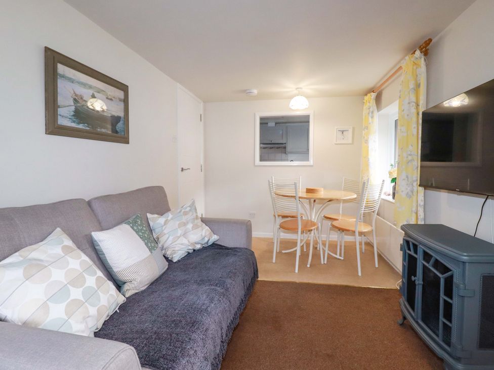 A living room with a sofa and dining area at The Penthouse in Looe