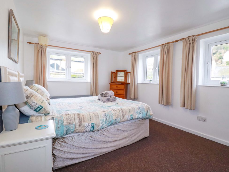 A bedroom with a bed and dresser at The Penthouse in Looe