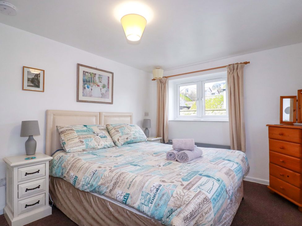 A bedroom with a bed and dresser at The Penthouse in Looe