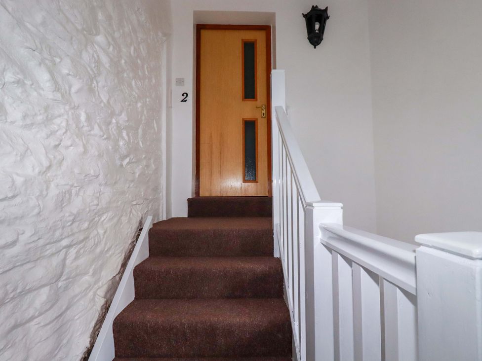 A staircase leading to a door marked with number 2 at The Penthouse in Looe