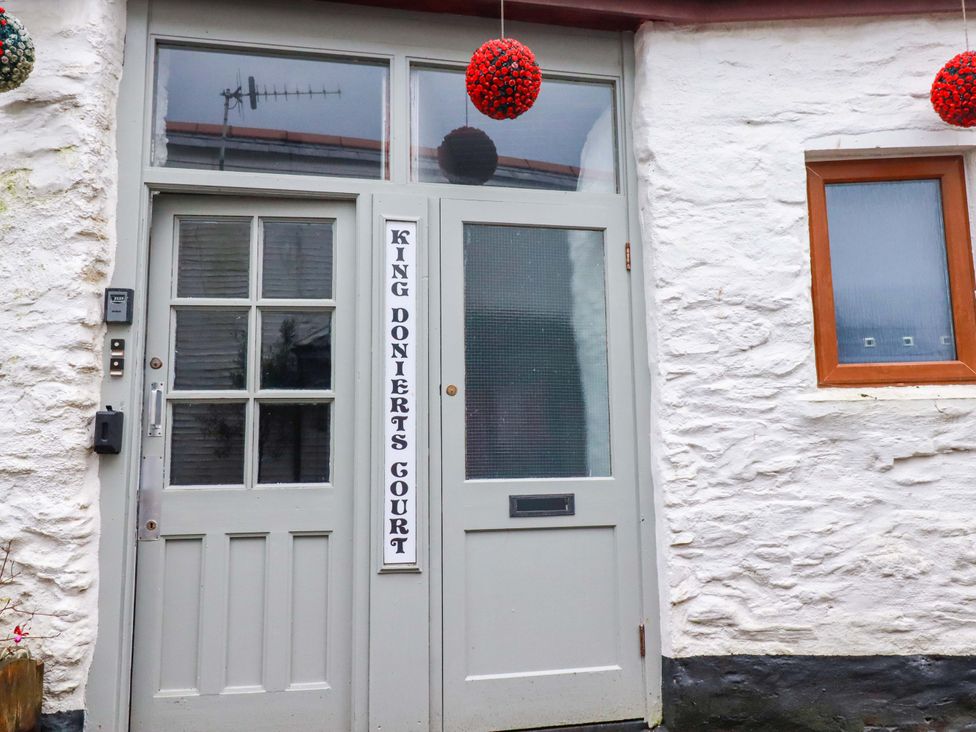 An entrance door with a sign and window at King Donierts Court in Looe