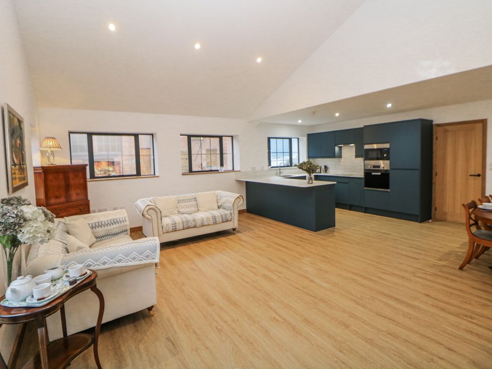 A living room with a sofa and kitchen area at Courtyard View Ashbourne