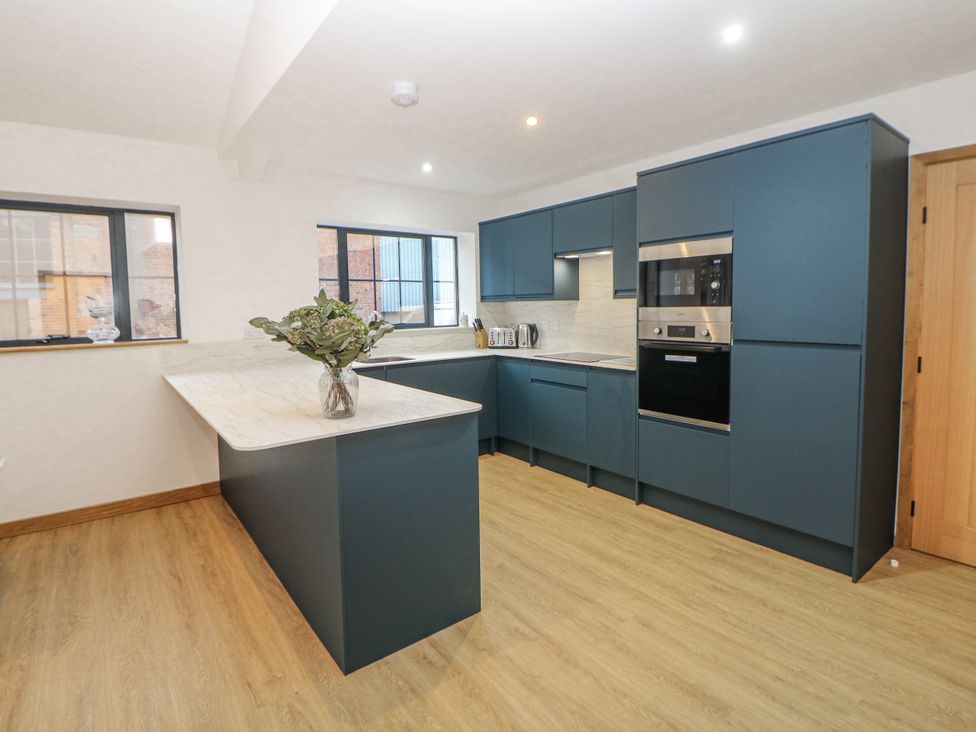 A kitchen with blue cabinets, countertop and appliances at Courtyard View, Ashbourne