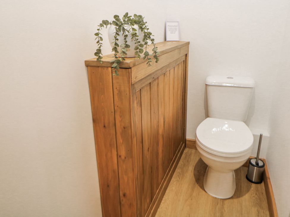 A bathroom with a toilet and wooden panel at Courtyard View Ashbourne