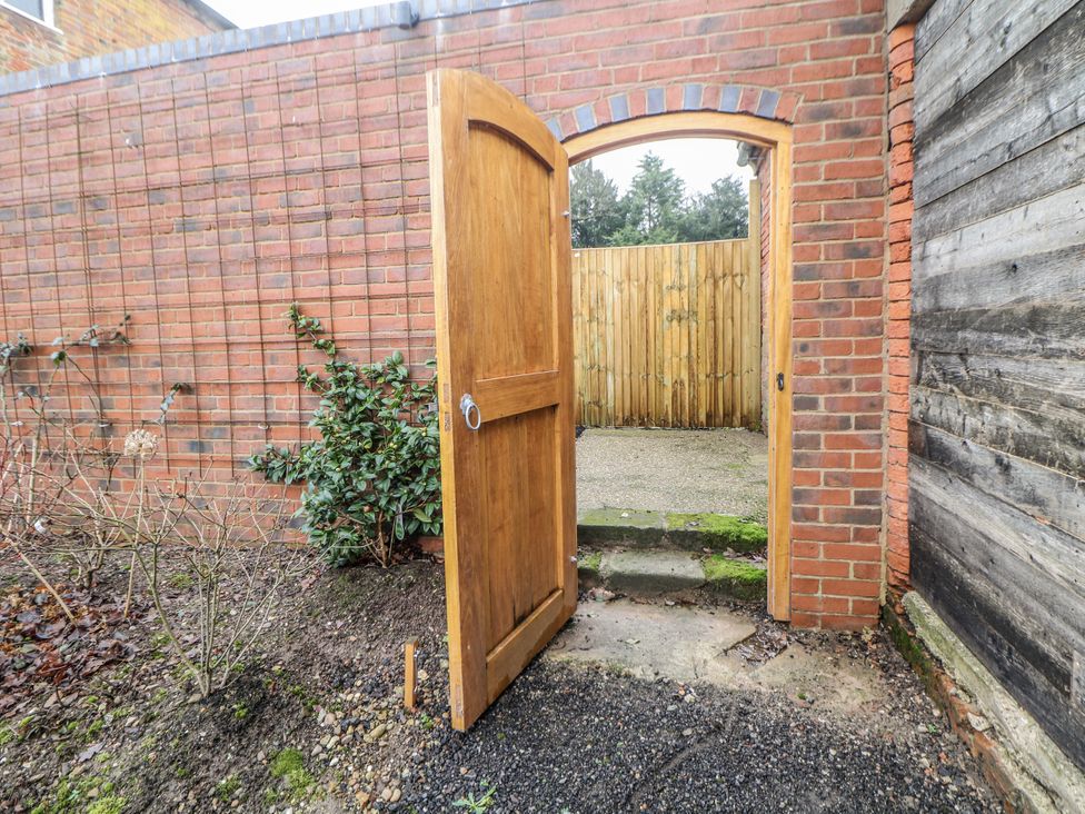 A garden path with a wooden door opening to a fenced area at Courtyard View Ashbourne