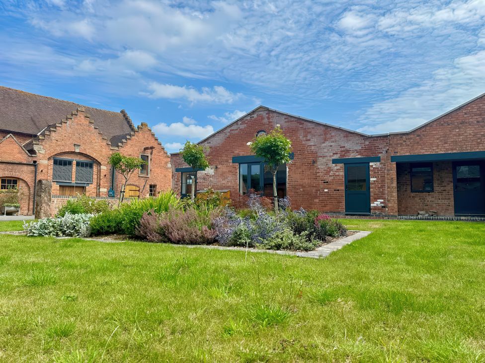 A brick building with grass and flowers at Courtyard View in Ashbourne