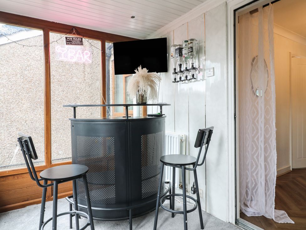 A bar area with stools and a television at 57 Howden Avenue Doncaster