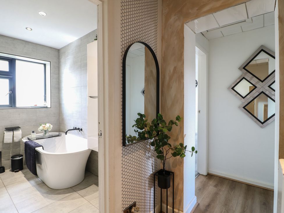 A bathroom with a bathtub and mirror at 57 Howden Avenue Doncaster