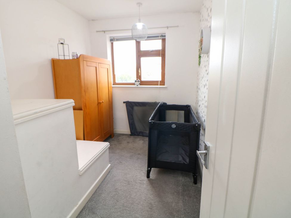 A bedroom with a cot and wardrobe at 57 Howden Avenue in Skellow