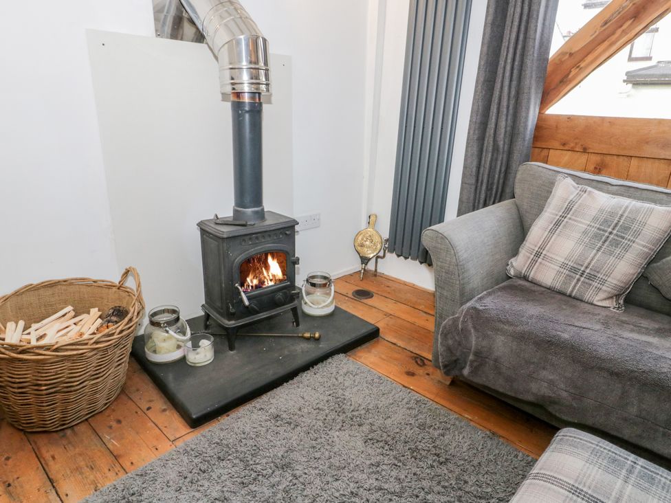A living room with a wood burning stove and sofa at Studio Bach in Beaumaris