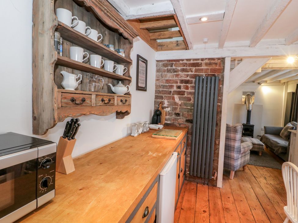 A kitchen with wooden shelf displaying cups and jars at Studio Bach in Beaumaris