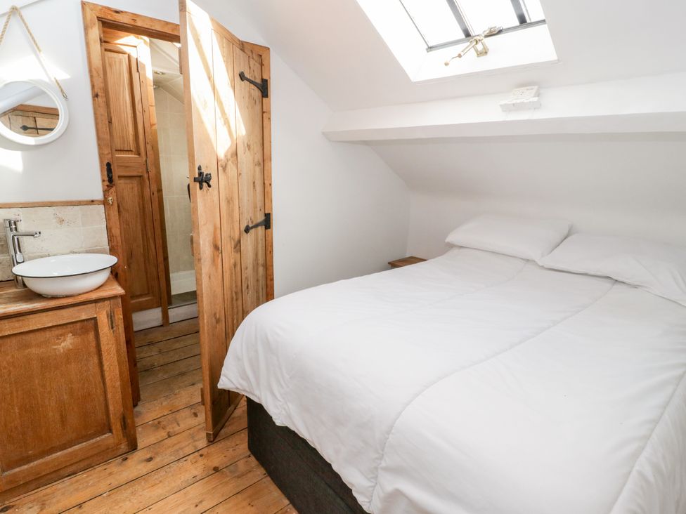 A bedroom with a bed and sink in the corner at Studio Bach in Beaumaris