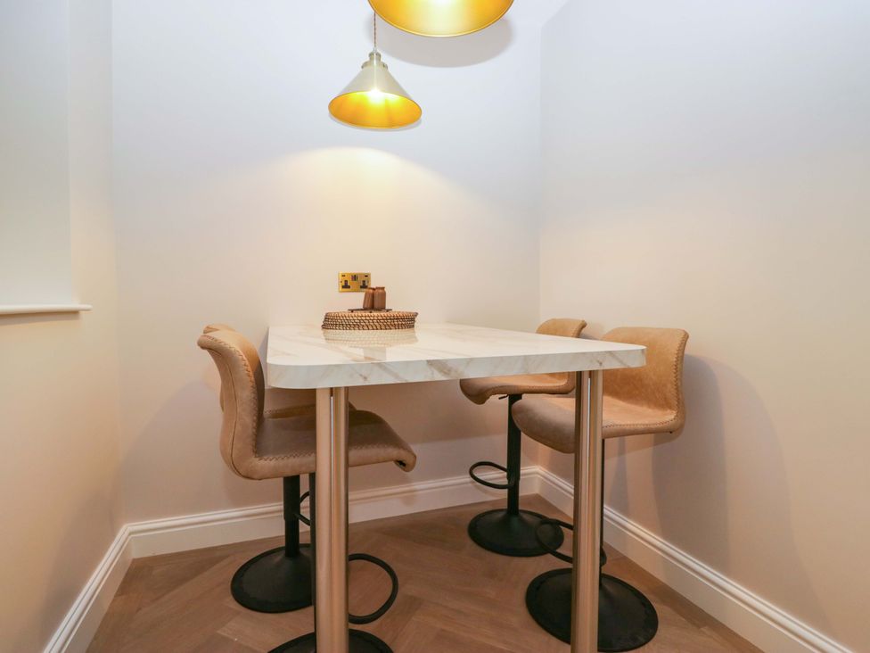 A dining area with a table and stools at Flat 5 Caxton House Windermere