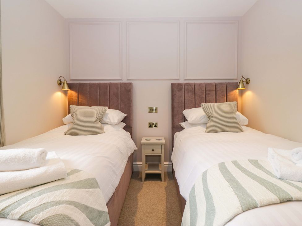A bedroom with two single beds and a bedside table at Flat 5 Caxton House in Windermere