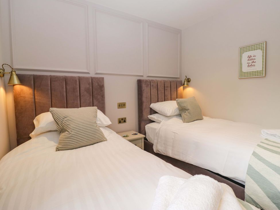 A bedroom with two beds and a lamp at Flat 5 Caxton House in Windermere