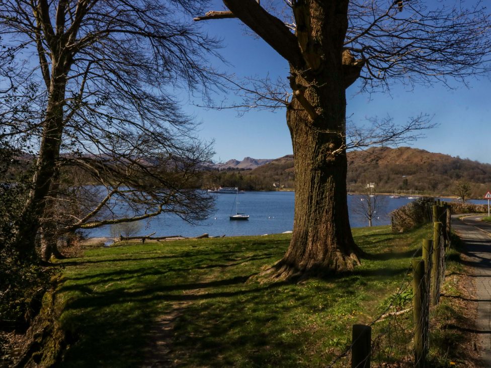 A view of a lake with trees and a boat at Flat 5 Caxton House, Windermere