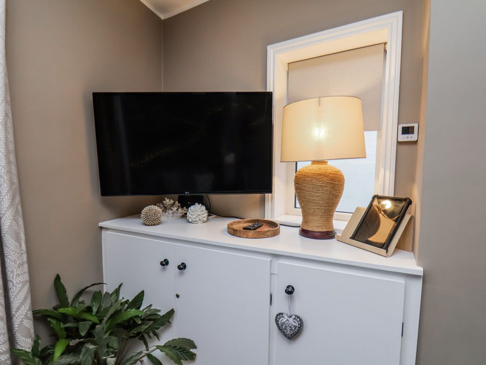 A living room with a television, lamp, and decorative items at Albion Cottage in Whitby