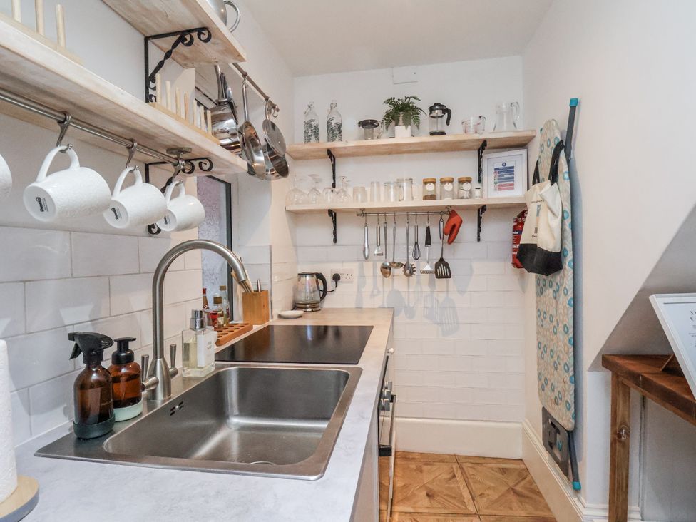 A kitchen with sink and shelves storing utensils and jars at Albion Cottage in Whitby