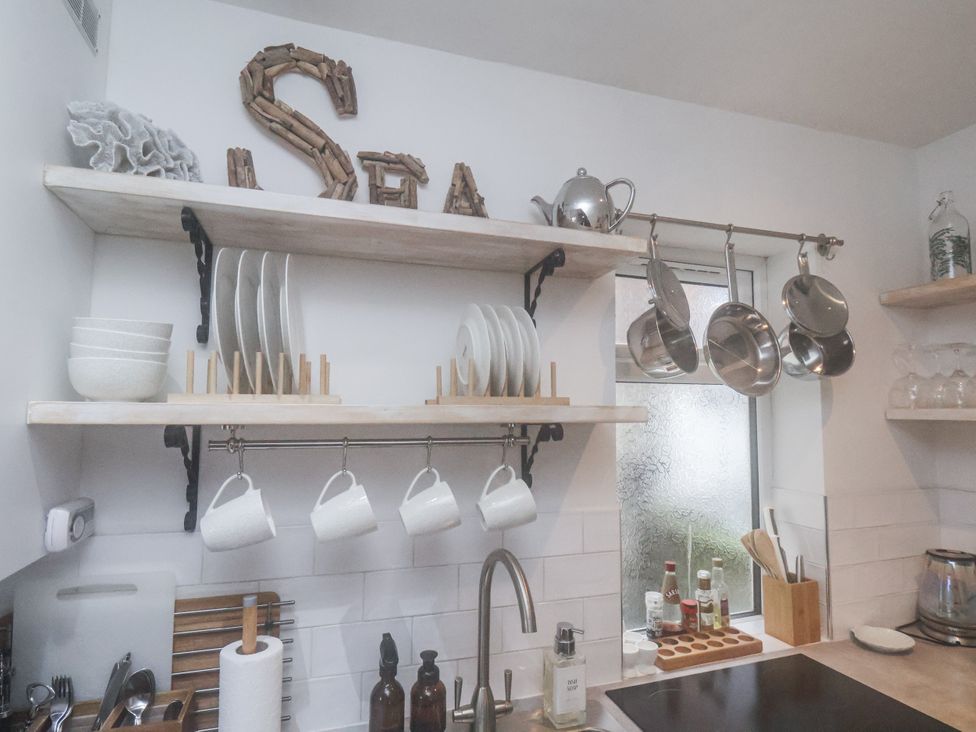 A kitchen area with shelves holding plates and mugs at Albion Cottage in Whitby