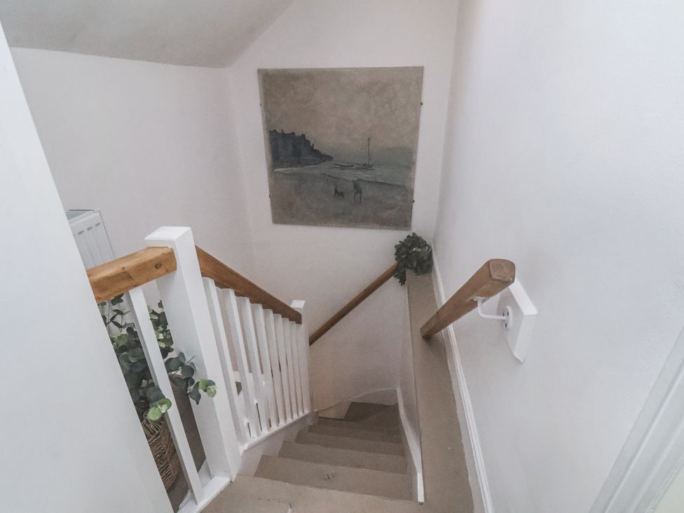 A staircase with a railing and a painting at Albion Cottage in Whitby