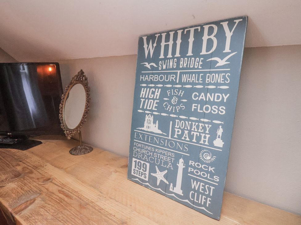 A living room with a decorative sign and a mirror at Albion Cottage in Whitby