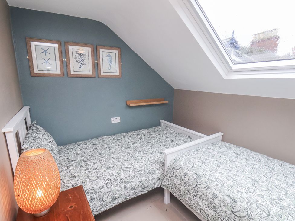 A bedroom with two beds and wall art at Albion Cottage in Whitby
