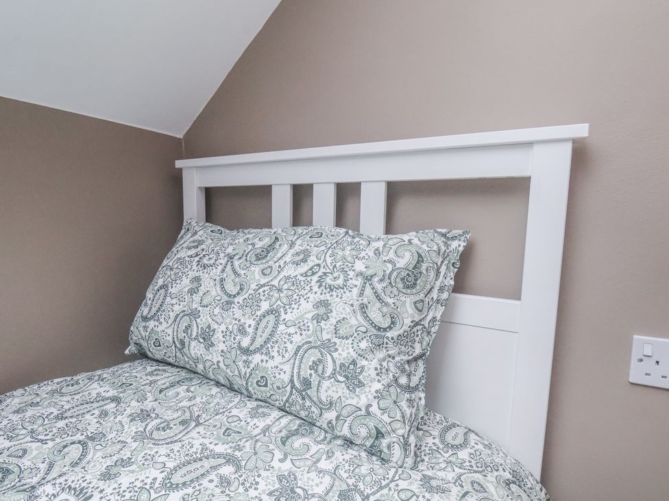 A bed with patterned bedding and pillows at Albion Cottage in Whitby