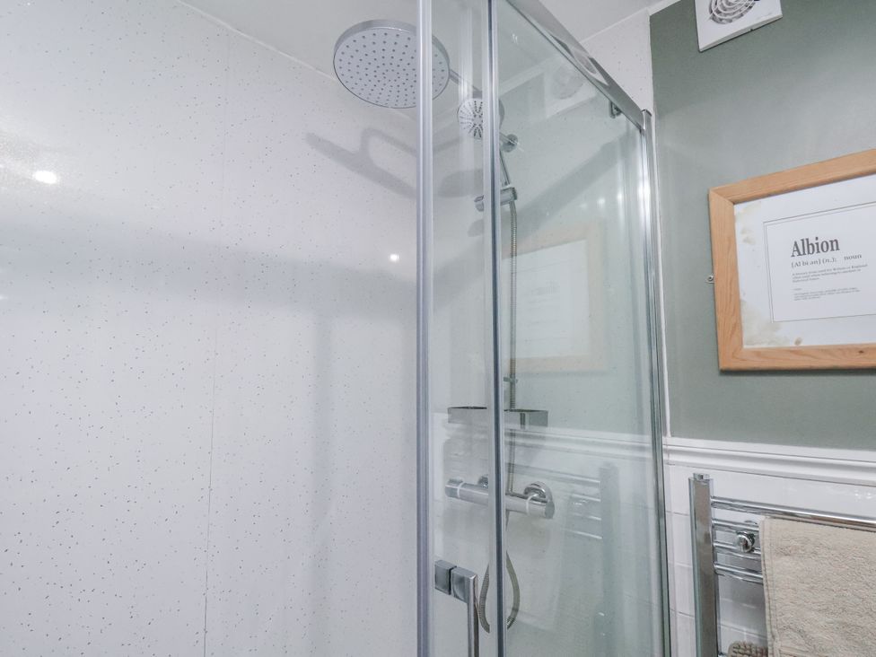 A shower with a glass enclosure and a towel rail at Albion Cottage in Whitby