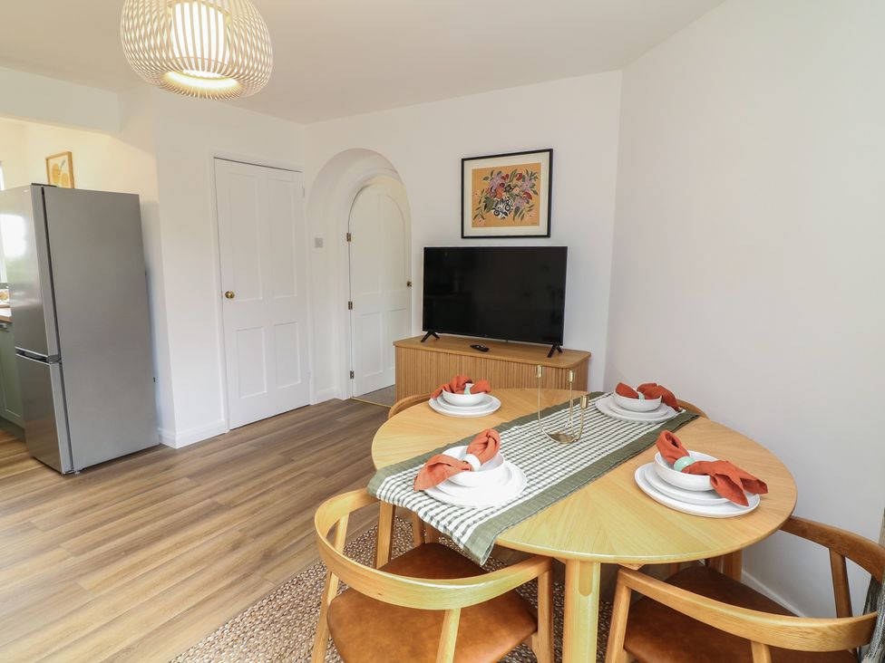 A dining room with a table and chairs and a television at Casthorpe Lodge Cottage Barrowby