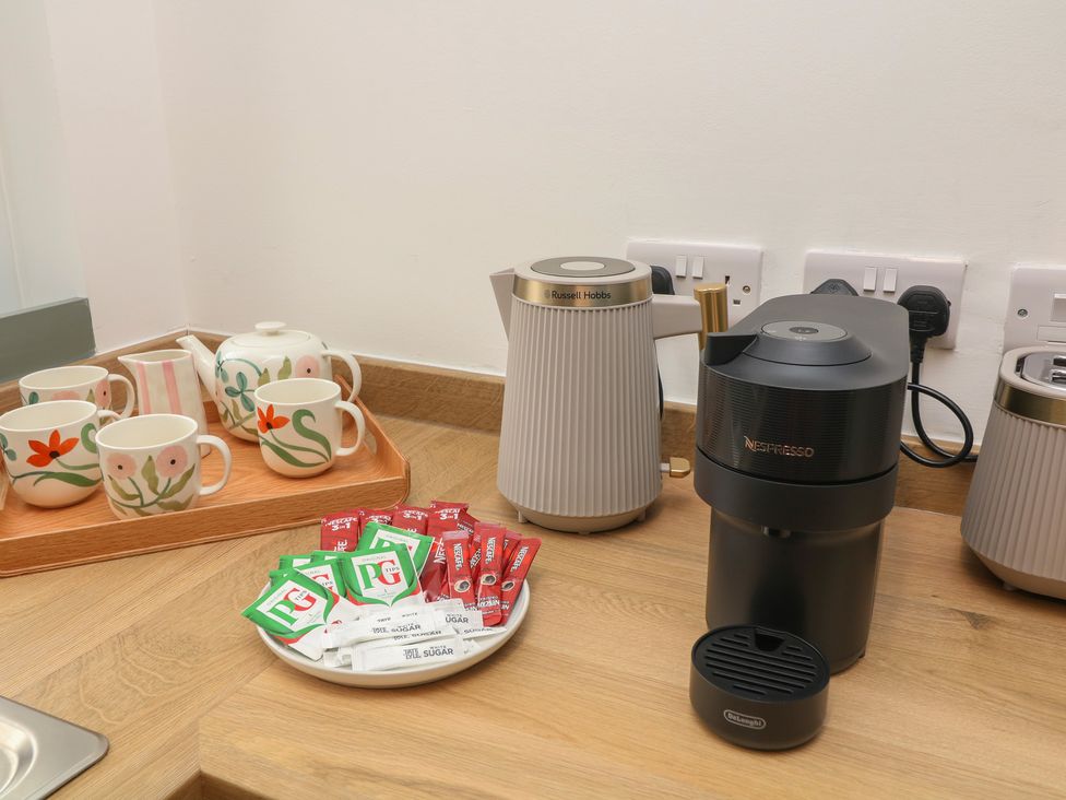 A coffee machine and mugs on a countertop at Casthorpe Lodge Cottage Barrowby