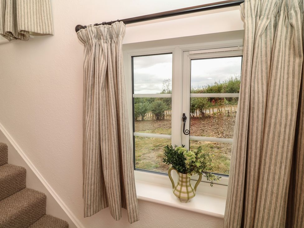 A staircase with a window and curtain at Casthorpe Lodge Cottage Barrowby