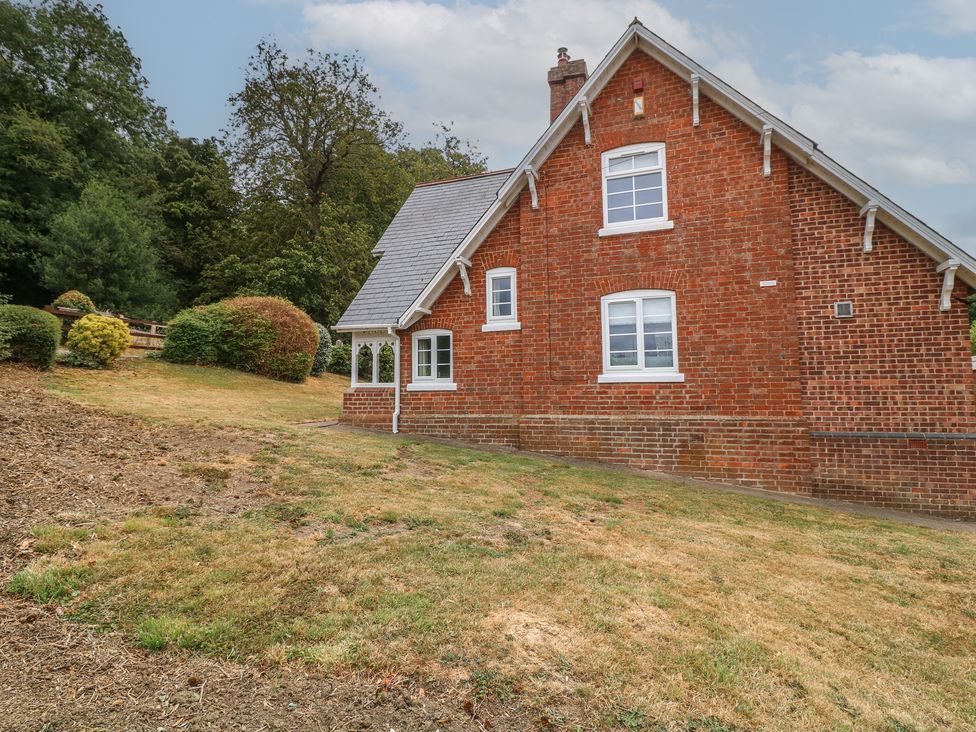 A brick house with windows and surrounding grass at Casthorpe Lodge Cottage Barrowby