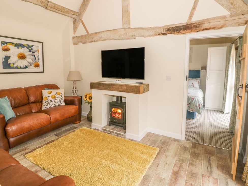 A living room with a sofa and television at Megs Cottage in Stratford-upon-Avon