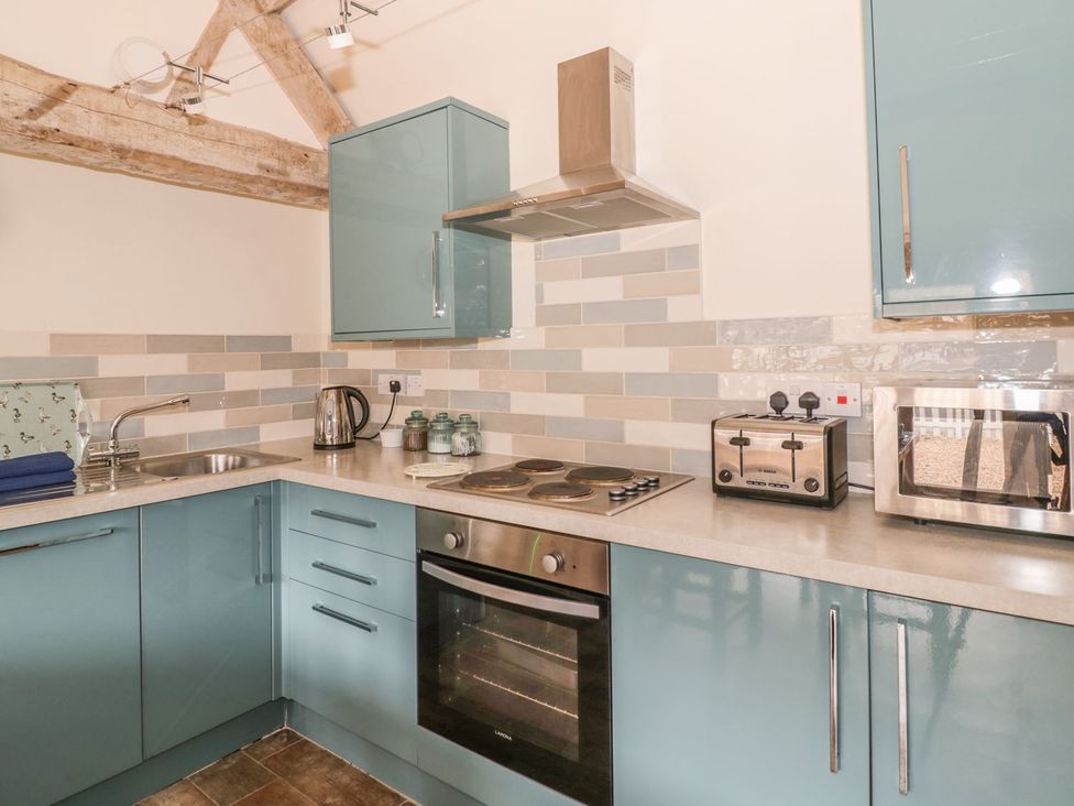 A kitchen with cabinets, an oven, a kettle, and a toaster at Megs Cottage in Stratford-upon-Avon