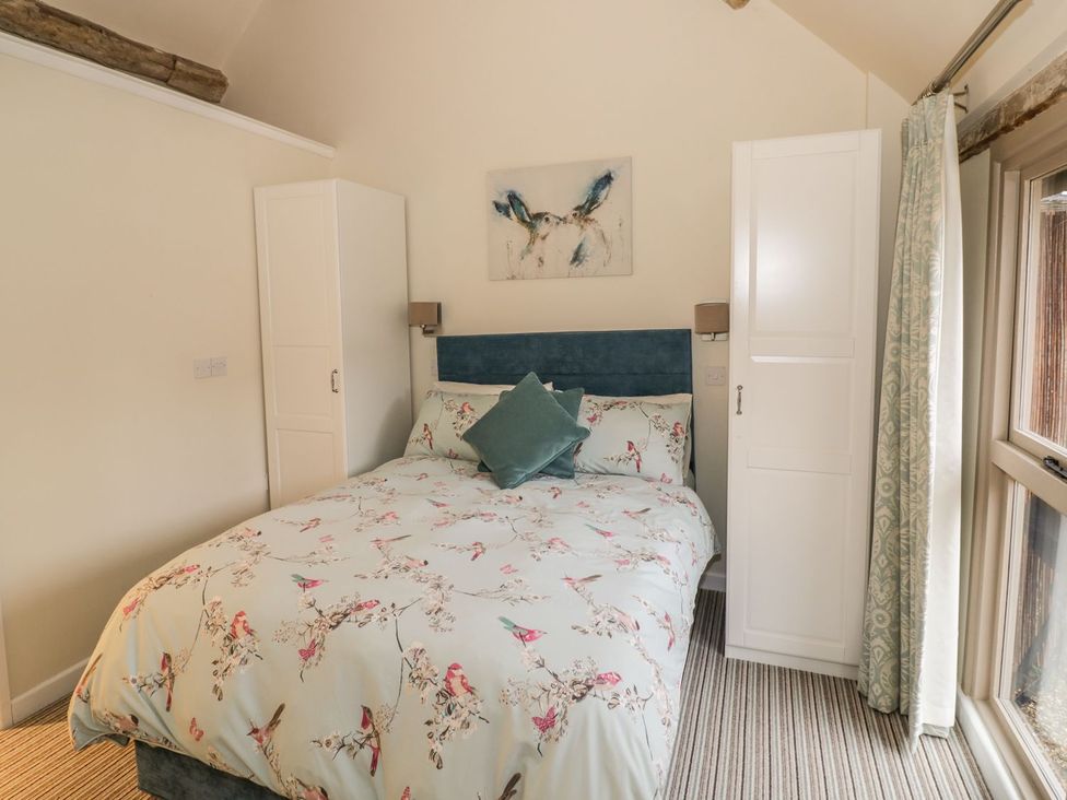 A bedroom with a bed and wardrobe at Megs Cottage in Stratford-upon-Avon