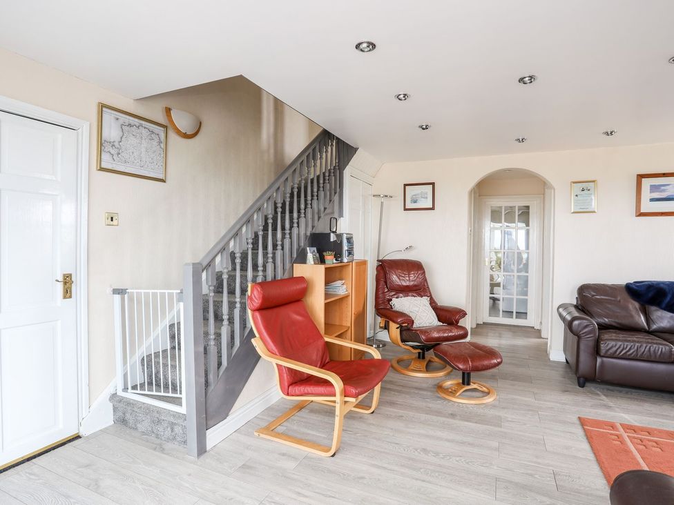A living room with a staircase and seating area at Bodlasan Groes Cottage in Holyhead