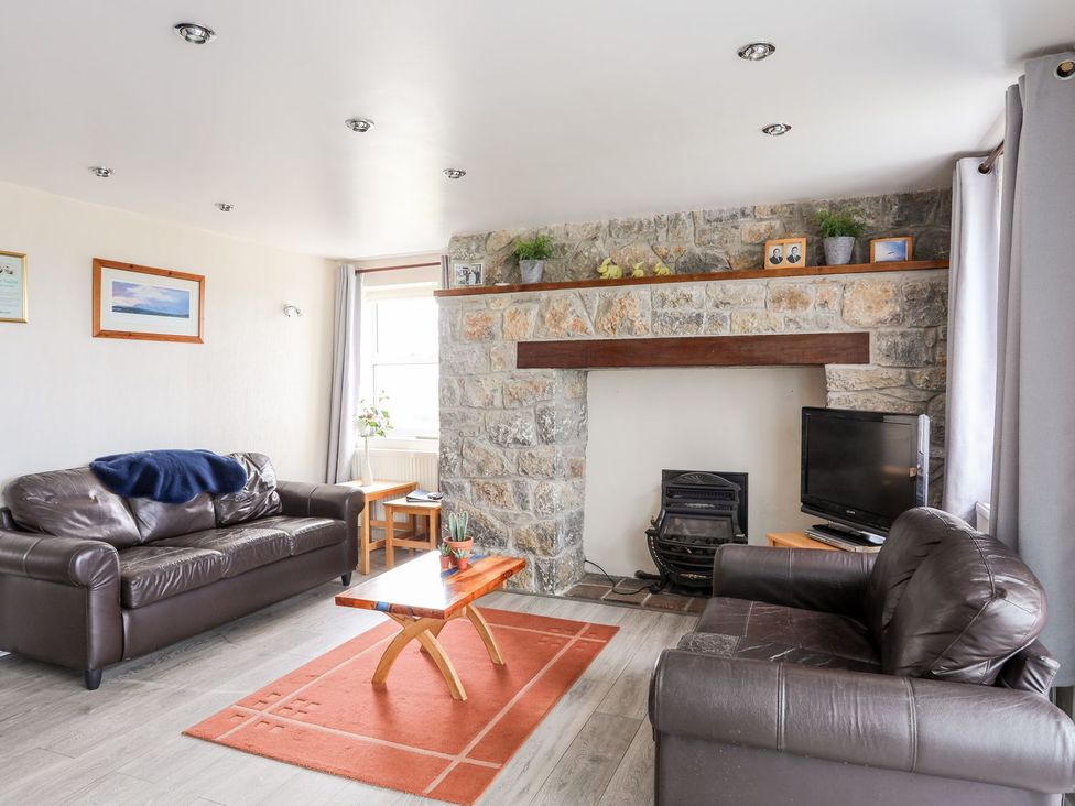 A living room with sofas and a fireplace at Bodlasan Groes Cottage in Holyhead