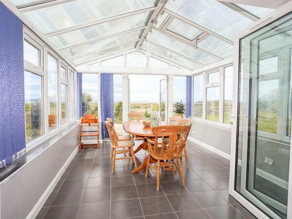 A conservatory with a dining table and chairs at Bodlasan Groes Cottage in Holyhead
