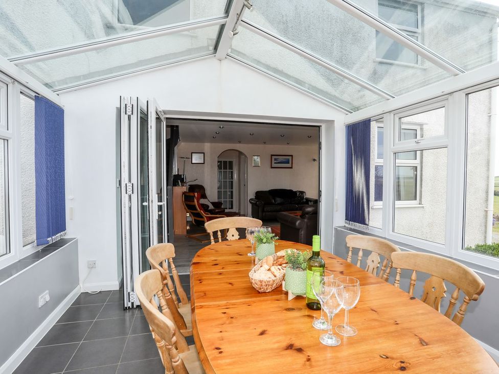 A conservatory with a wooden table and chairs at Bodlasan Groes Cottage Holyhead