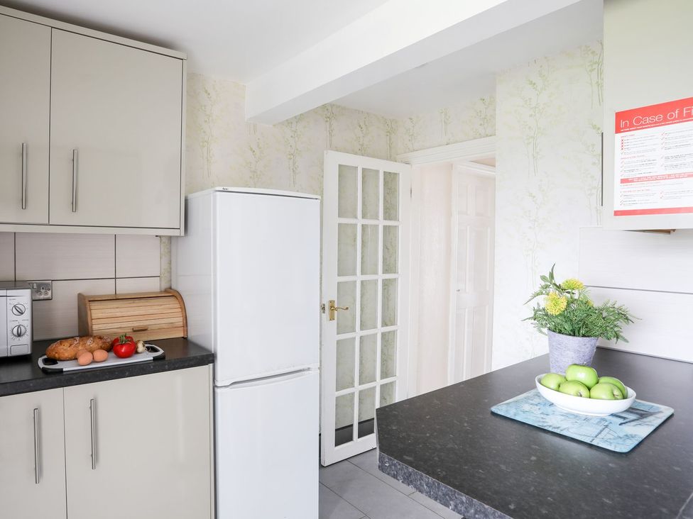 A kitchen with a fridge and a bowl of apples at Bodlasan Groes Cottage in Holyhead