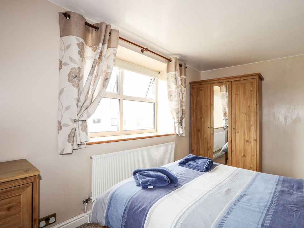 A bedroom with a bed and wardrobe at Bodlasan Groes Cottage in Holyhead