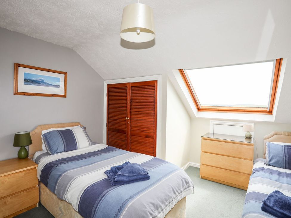 A bedroom with two beds and a window at Bodlasan Groes Cottage, Holyhead