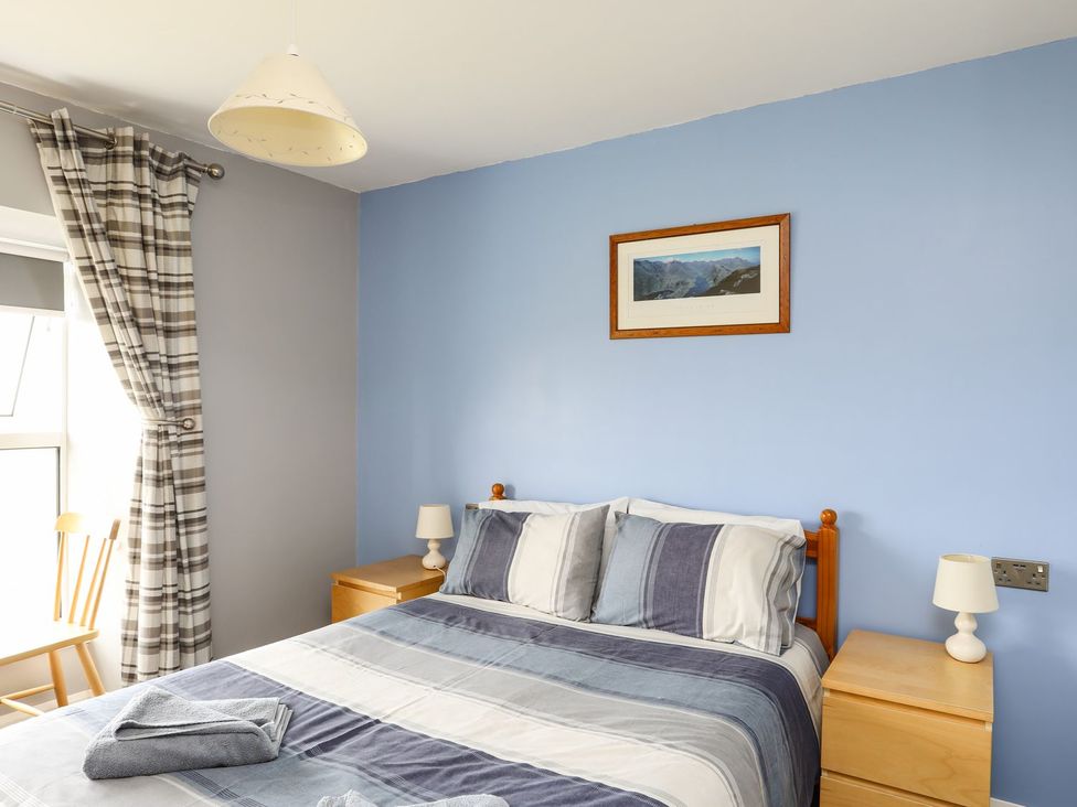 A bedroom with a bed, bedside table and chair at Bodlasan Groes House in Holyhead