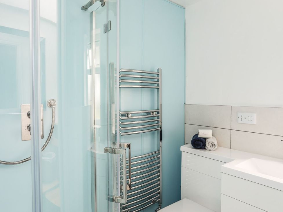 A bathroom with a shower and towel rack at Bodlasan Groes House, Holyhead