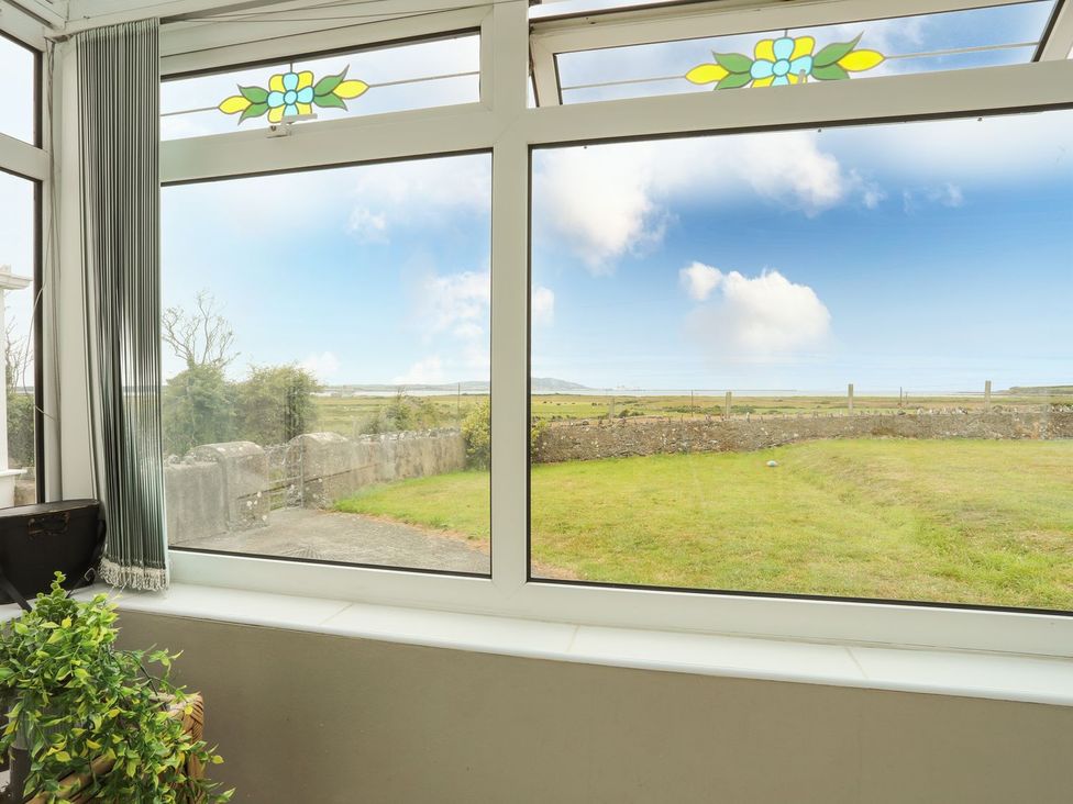 A conservatory with large windows and greenery at Bodlasan Groes House in Holyhead