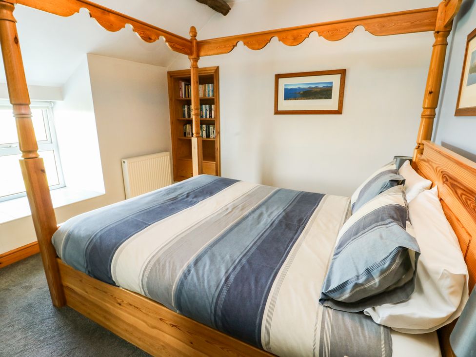 A bedroom with a four-poster bed and bookshelf at Bodlasan Groes House Llanfachraeth