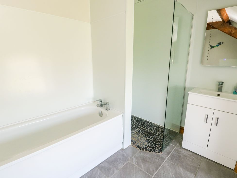 A bathroom with a bathtub and a shower at Bodlasan Groes House Llanfachraeth